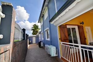 a blue and yellow house with a walkway outside at Dom pension in Baie-Mahault