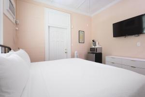 Un dormitorio con una cama blanca y un televisor de pantalla plana. en Creme Brulee Suite, en Key West