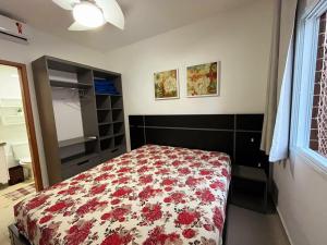 a bedroom with a bed with a floral bedspread at Apto Praia das Toninhas in Ubatuba