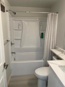 a white bathroom with a tub and a toilet at Dunique unique home in Winnipeg +10 photos