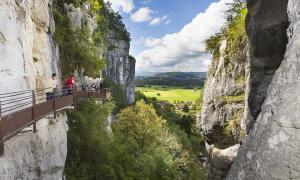Un grupo de personas de pie en un puente entre dos montañas. en Gite de la Cure Gourmande, en Saint-Christophe