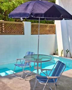 a table and chairs under an umbrella next to a pool at Apartamento de playa con piscina privada in Monterrico