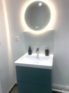 a bathroom with a sink and a round mirror at La petite Catène in Le Havre