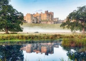 a castle with its reflection in a lake at The View Point Northumberland in Newton on the Moor