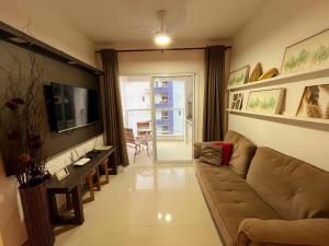 a living room with a couch and a television at Apto Praia das Toninhas in Ubatuba