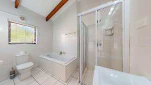 Un baño blanco con inodoro y ducha. en Lake House at San Lameer, en Southbroom 21 fotos más