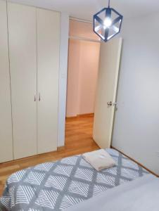 Schlafzimmer mit einem Bett und einer Leuchte in der Unterkunft Amplio y Acogedor, cerca al parque de las aguas in Víctor Larco Herrera