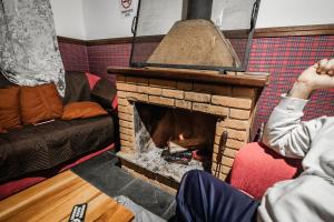a person sitting in front of a brick fireplace at Chalé Suiço de Campos do Jordão in Campos do Jordão