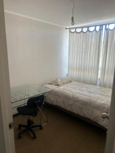 a bedroom with a desk and a bed and a glass table at Departamentokilaman in Concepción