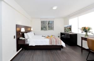 a white bedroom with a bed and a desk and a desk at MR Express (ex Hotel Neruda Express) in Santiago