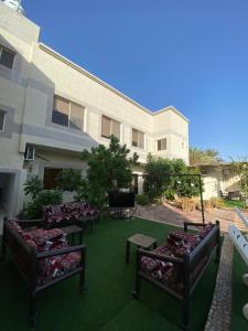 a group of benches sitting on a lawn in front of a building at فيلا وشاليه الجبل الاحمر in Al-ʿUla