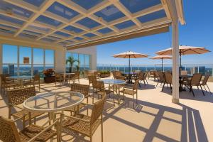 a patio with tables and chairs with a view of the ocean at Saint Moritz Hplus Express in Brasília +27 photos