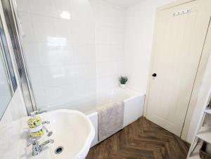 ein weißes Badezimmer mit Waschbecken und Badewanne in der Unterkunft Beautiful Waterfall Cottage with Countryside Walks in Barnoldswick + 5 Fotos