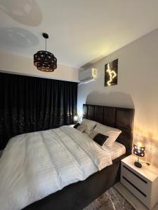 a bedroom with a large white bed and a chandelier at Andra Rezidence in Popeşti-Leordeni