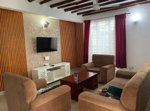 ウクンダにあるNuru's 3BR Diani Villa - 4 Mins To The Beachのソファと椅子とテレビのあるリビングルーム