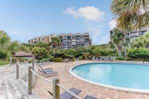 a swimming pool with chairs and a building in the background at Oceanfront 3 Bedrooom BeachWalker Condo in Amelia Island