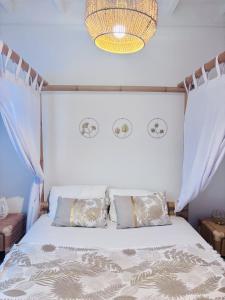 a bedroom with a white bed with curtains and a chandelier at Le Mohana - L'évasion tropicale de l'Est in Saint-André