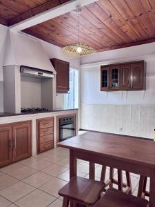 a kitchen with a wooden table and a wooden ceiling at Le Mohana - L'évasion tropicale de l'Est in Saint-André