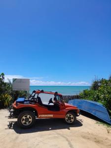 ein kleiner roter Jeep, der am Strand geparkt ist in der Unterkunft Casas Araras de Corumbau, Piscina, a 5 Min da Praia in Corumbau