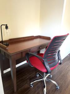 a red chair sitting in front of a wooden desk at Lincoln Inn Fredericton in Fredericton