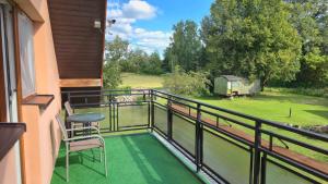 a balcony with a table and chairs and a view of a field at Mazury Apartament/Dom z ogródkiem całoroczny przy jeziorze in Sędańsk
