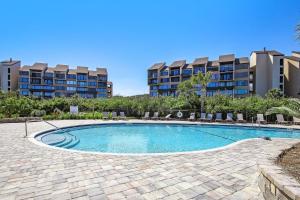 FranklintownにあるEnjoy breathtaking views of the Atlantic Ocean in this three bedroom three bath villaの背景に椅子と建物のあるスイミングプール