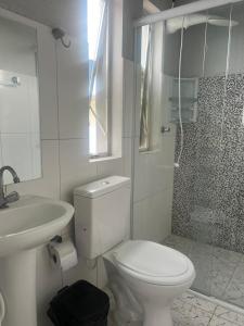 a white bathroom with a toilet and a sink at Pousada Spa Peruíbe in Peruíbe