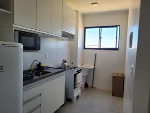 a kitchen with white cabinets and a sink and a window at Apto com dois quartos com cama e ar in Juazeiro do Norte +4 photos