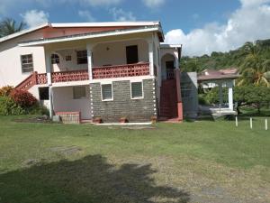 a white house with a porch and a yard at Little paradise in Saint Georgeʼs