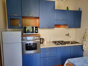 a kitchen with blue cabinets and a microwave on top of a stove at CASA VACANZE NONNO ASTERIO in Monfalcone