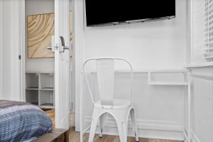 a white chair in a bedroom with a tv on the wall at Pittsburgh Shadyside 2A Bright and Stylish Private Bedroom with Shared Bathroom in Pittsburgh