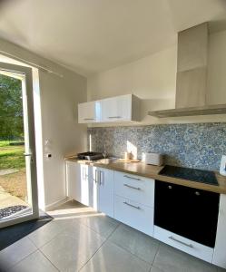 a kitchen with white cabinets and a large window at La Petite Vitesse in La Flèche