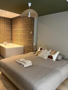 a bedroom with a large bed and a bath tub at Suite Romantique - Love Room Valence Amour et Bulles - Jacuzzi - Lit king size avec miroir XXL - Sofa Tantra - Drôme Ardèche in Bourg-lès-Valence