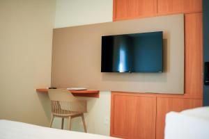 a room with a desk and a television on a wall at Farms Hotel in Coribe