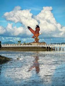 Langkawi IslandsにあるRoamia Retreat - Seaview 111 - 3 BHK Seafacing apartmentの鷲の像を持って水の中に立っている人