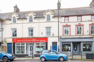 Un coche azul aparcado delante de un edificio en Llangefni Town Centre 3 Bed Apt & Free Parking, en Llangefni