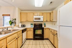 a kitchen with wooden cabinets and a white refrigerator at Beaches and Birdies in North Myrtle Beach +21 photos