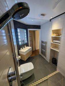 a bathroom with a sink and a tub and a toilet at The Lawns Spa Apartment in Holt