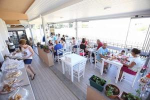 a group of people sitting at tables in a restaurant at Ede Apart Otel in Geyikli