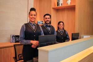 a man and two women standing in front of a desk at Farms Hotel in Coribe
