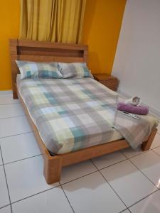 a bed with a plaid comforter and two towels on it at Un logement unique et spacieux face à la mer in Saint-Louis