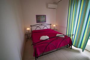 a bedroom with a red bed with two lamps and a window at Orizzonte Mare in Fontane Bianche