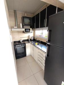 una cucina con frigorifero nero e armadietti bianchi di CASA en Olavarría - Pueblo Nuevo a Olavarría