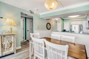a kitchen and dining room with a wooden table and white chairs at Sands Beach Club 1015 - Bright Shores in Myrtle Beach