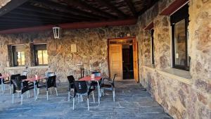 un patio con mesas y sillas en un edificio de piedra en Hostal Las Cavenes Del Cabaco, en El Cabaco