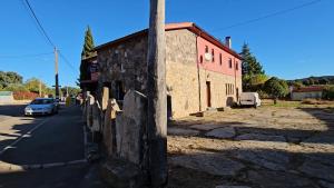 Un antiguo edificio de piedra al costado de una calle. en Hostal Las Cavenes Del Cabaco, en El Cabaco
