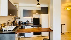 a kitchen with black cabinets and a white refrigerator at Appartement Cosy et calme - face à la gare Rosny-sous-Bois - 20mn de Paris et Disneyland in Rosny-sous-Bois