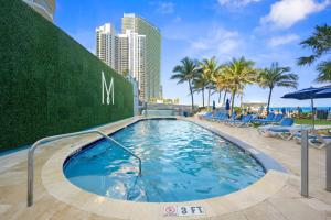 a large swimming pool with chairs and palm trees at Marenas Resort PRIVATE UNIT daily refresh not included in Sunny Isles Beach