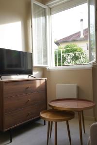 ein Wohnzimmer mit einem Tisch, einem TV und einem Fenster in der Unterkunft Le Fleury in Fontenay-le-Fleury