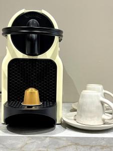 eine schwarz-gelbe Kaffeemaschine auf einem Tisch mit einem Teller in der Unterkunft Le Fleury in Fontenay-le-Fleury + 10 Fotos